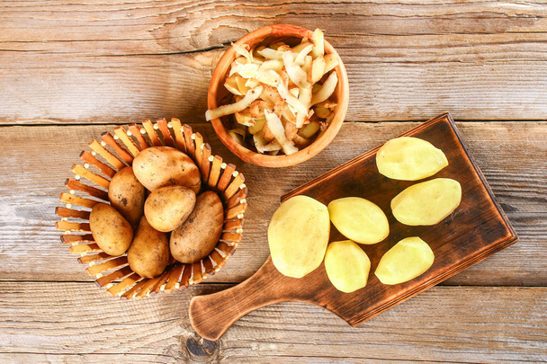 Men's hands clean potatoes for okroshki on an old wooden table. - Foto, Imagen