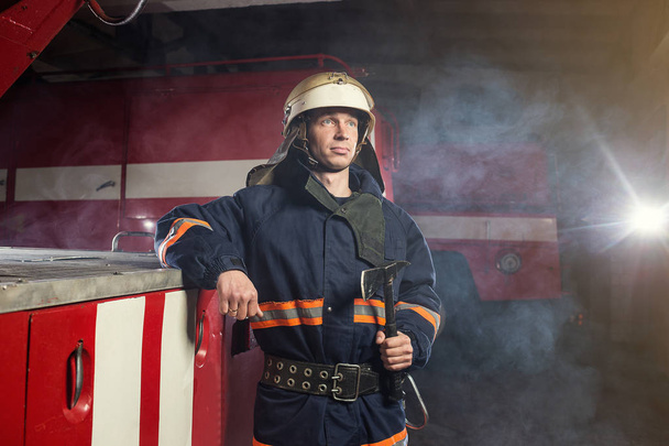 Pompier (pompier) en action debout près d'un camion de pompiers. Sécurité d'urgence. Protection, sauvetage du danger
. - Photo, image