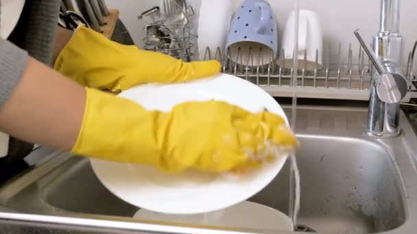 Closeup 4k footage of housewife washing off detergent suds from dishes in kitchen sink - Footage, Video