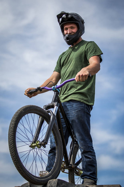 Спортсмен в шлеме стоит на велосипеде
 - Фото, изображение