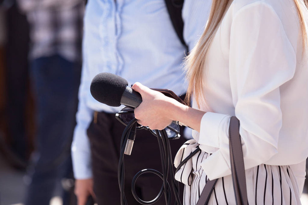 Female journalist holding microphone - 写真・画像