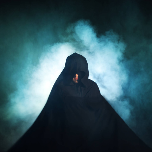Gloomy image. Man in a black cloak. Demonic image. Magician illusionist - 写真・画像