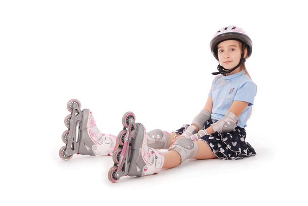 Happy little girl with roller skates and protective gear resting. - Fotó, kép