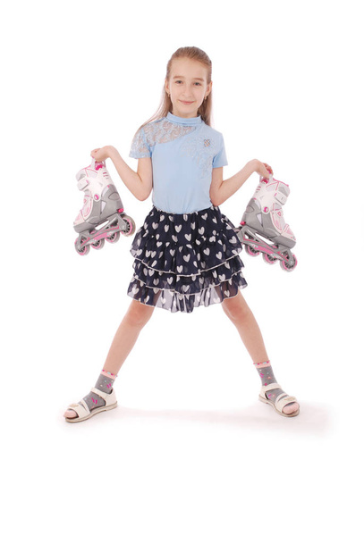 Gelukkig klein meisje houdt in handen rolschaatsen - Foto, afbeelding