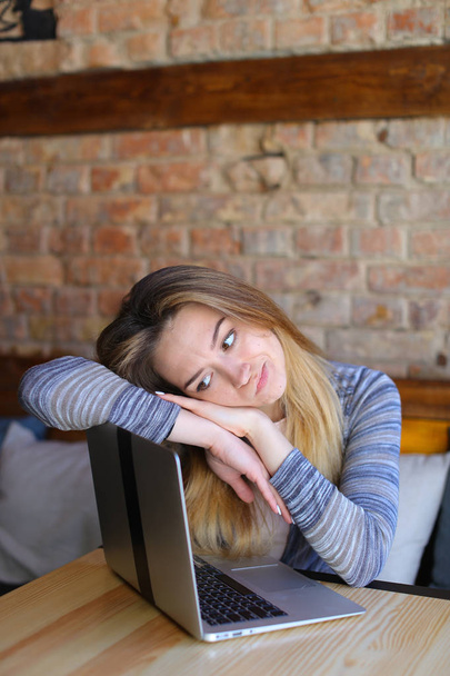 Καυκάσιος κορίτσι που κάθεται κοντά σε φορητό υπολογιστή στο café. - Φωτογραφία, εικόνα