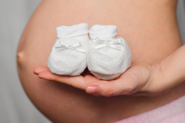 buciki dla noworodka w rękach dziewczyna w ciąży - Zdjęcie, obraz