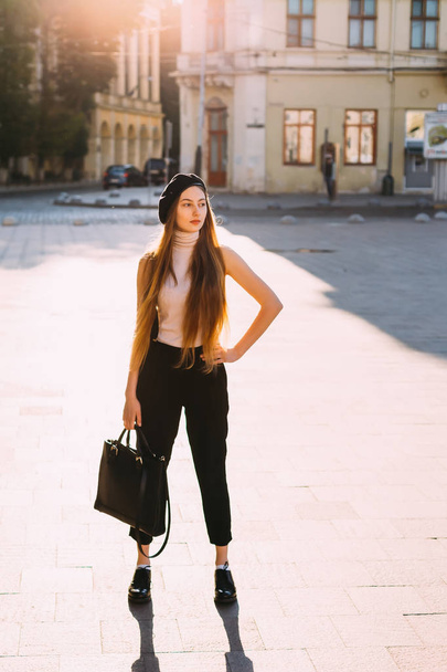 graceful girl with a black handbag in his hands and standing on  - Foto, Imagen