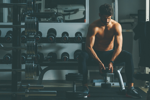 Portrait of strong and handsome young man doing exercise with dumbbells - Photo, Image