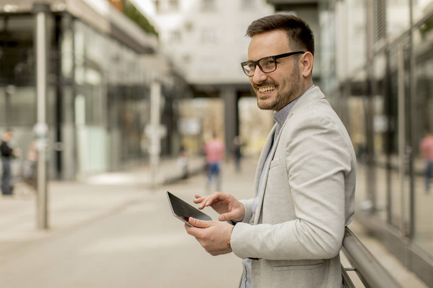 Portret młodego biznesmena, trzymając tablet cyfrowy odkryty w środowisko miejskie - Zdjęcie, obraz