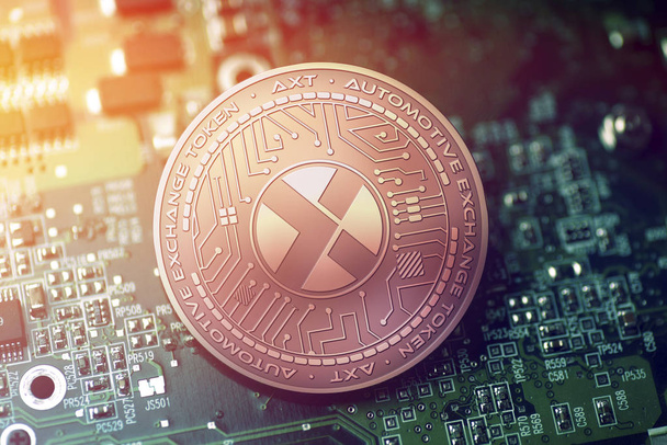 shiny copper AXT cryptocurrency coin on blurry motherboard background - Photo, Image