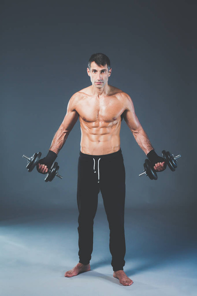 Handsome muscular man working out with dumbbells. Personal fitness instructor. Personal training. - Photo, Image