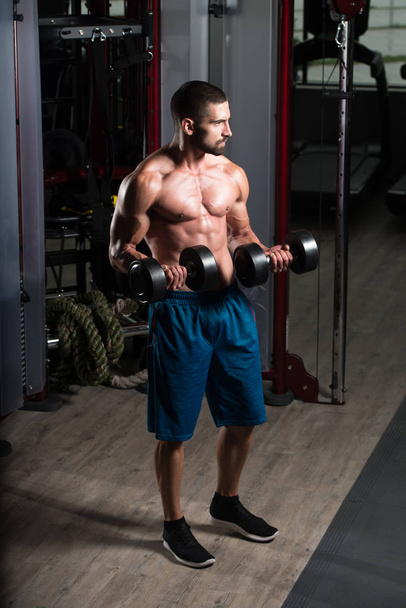 Biceps Exercise With Dumbbells In A Gym - Foto, immagini