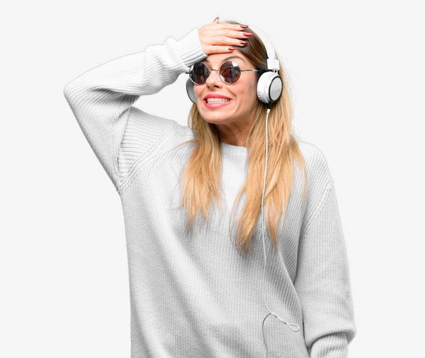 Young woman listen to music with headphone terrified and nervous expressing anxiety and panic gesture, overwhelmed - Foto, imagen