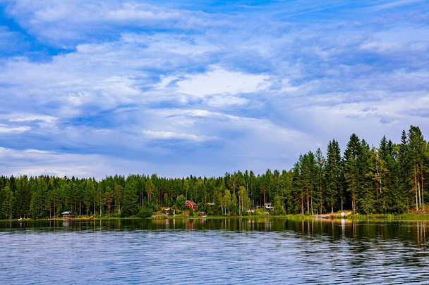Idyllic countryside landscape view with blue lake and house on the shore. Summer cottage in Finland. - Photo, Image