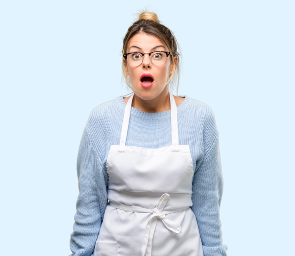 Young woman shop owner, wearing apron scared in shock, expressing panic and fear - Photo, Image