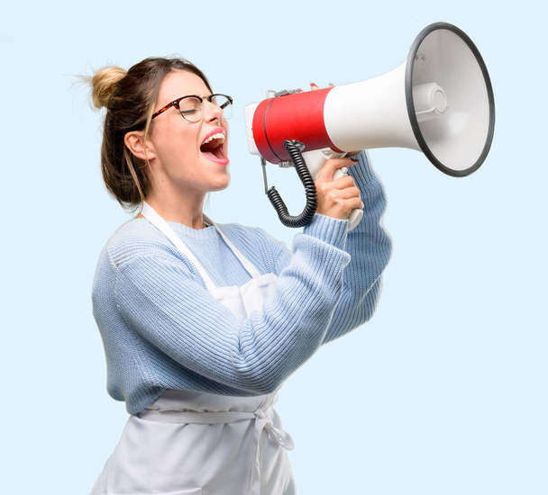 Jovem dona de loja, vestindo avental comunica gritando alto segurando um megafone, expressando sucesso e conceito positivo, ideia de marketing ou vendas
 - Foto, Imagem