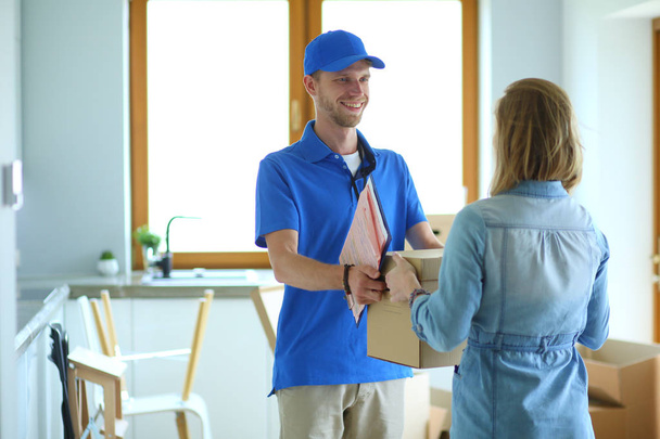 Smiling delivery man in blue uniform delivering parcel box to recipient - courier service concept. Smiling delivery man in blue uniform - Фото, зображення