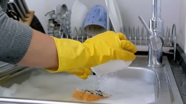 Closeup slow motion video of housewife in rubber gloves washing dishes on kitchen - Footage, Video