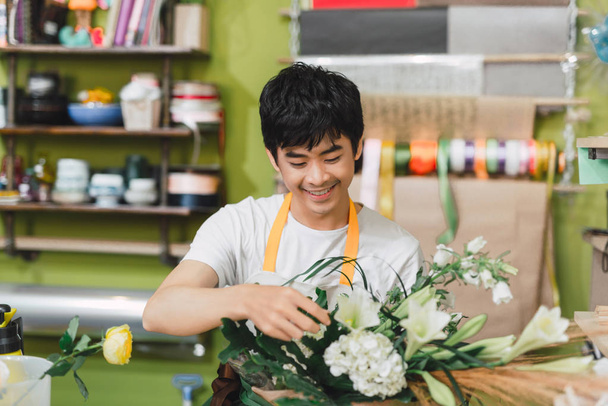Feliz asiático florista masculino fazendo buquê trabalhando na loja de flores
 - Foto, Imagem