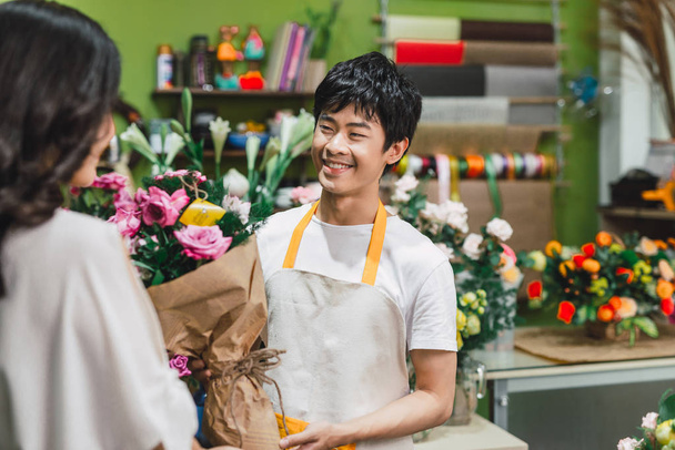 Masculino florista oferecendo flores no balcão na loja de flores
 - Foto, Imagem