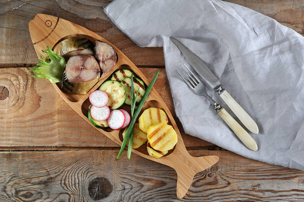 smoked mackerel, fried zucchini and potatoes in a dish shaped li - Foto, Imagen