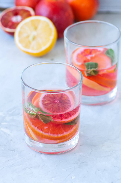 Refreshing blood orange water or infused water in a glass on a w - Photo, image