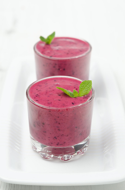 Blueberry smoothie with mint in a glass beaker on a white plate - Photo, Image