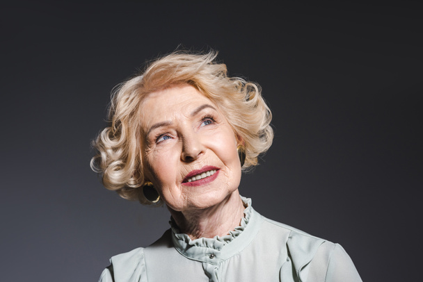 portrait en gros plan d'une femme âgée réfléchie regardant vers le haut sur le gris foncé
 - Photo, image