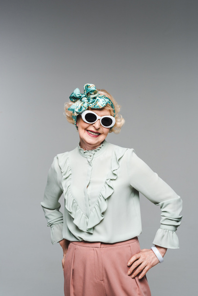 happy senior woman in stylish headband and sunglasses isolated on grey - Fotografie, Obrázek