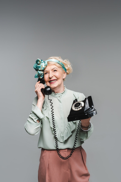 ευτυχής ανώτερος γυναίκα μιλάει με περιστροφικό τηλέφωνο που απομονώνονται σε γκρι - Φωτογραφία, εικόνα