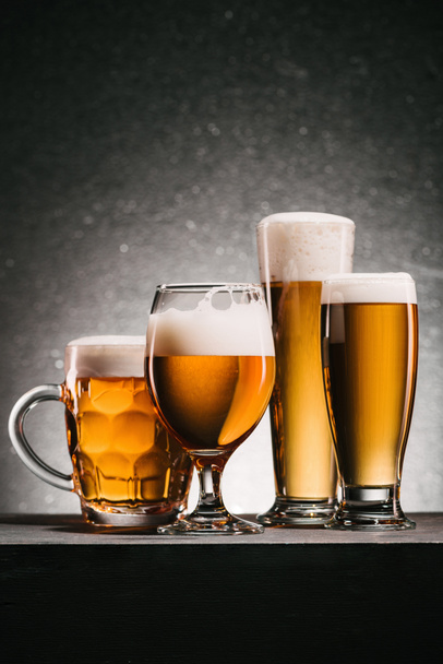 close up view of mugs of cold beer with foam on grey background - Фото, изображение