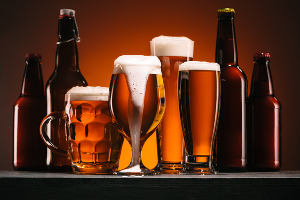 vista da vicino di bottiglie e tazze di birra su sfondo arancione
 - Foto, immagini