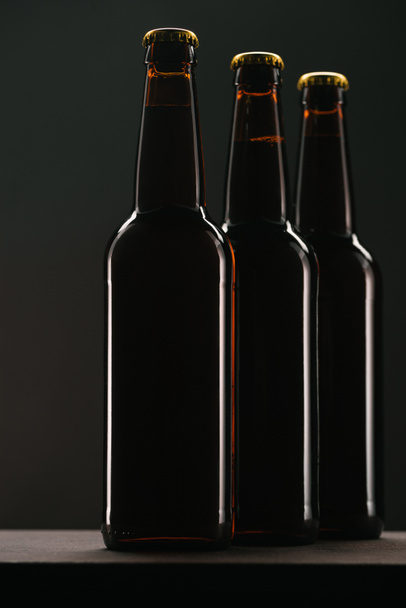 close up view of arranged bottles of beer on dark backdrop - Zdjęcie, obraz