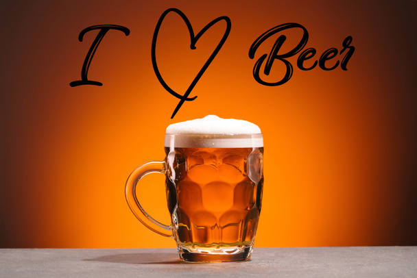 κλείνω πάνω θέα του κούπα της κρύας μπύρας και μου αρέσει μπύρα γράμματα σε πορτοκαλί φόντο - Φωτογραφία, εικόνα
