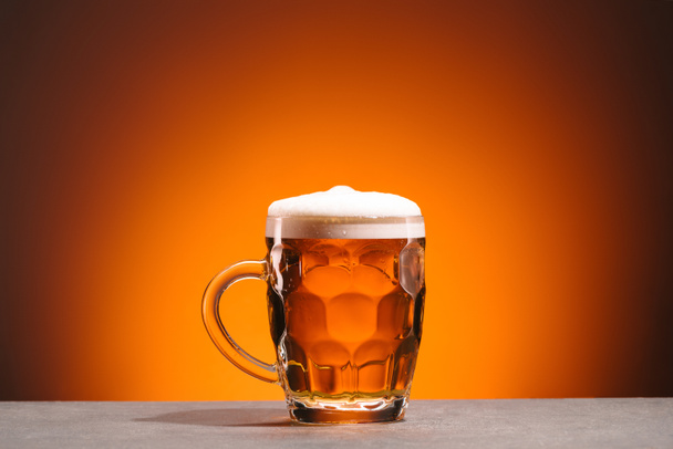 vista de cerca de taza de cerveza fría sobre fondo naranja
 - Foto, imagen