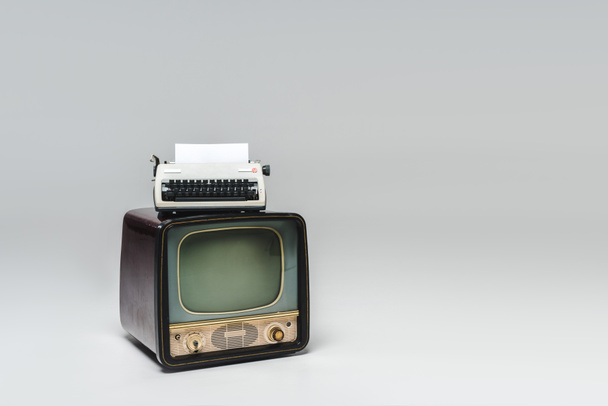tv vintage con máquina de escribir en la parte superior en la superficie gris
 - Foto, imagen