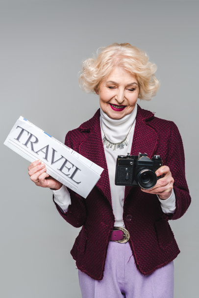 όμορφη γυναίκα ανώτερος με ταξίδια εφημερίδα και φιλμ κάμερας απομονώνονται σε γκρι - Φωτογραφία, εικόνα