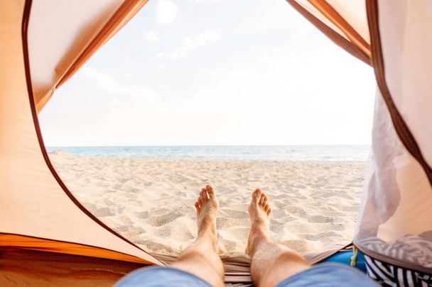 Man resting in a tent on sand beach.  - 写真・画像