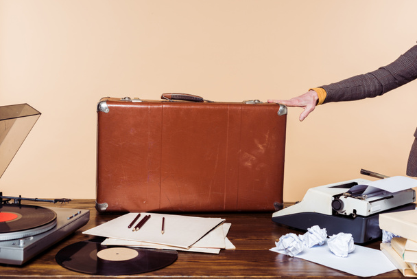Colpo ritagliato di mano femminile tenuta su valigia vintage sul tavolo con macchina da scrivere, disco in vinile e giradischi
  - Foto, immagini