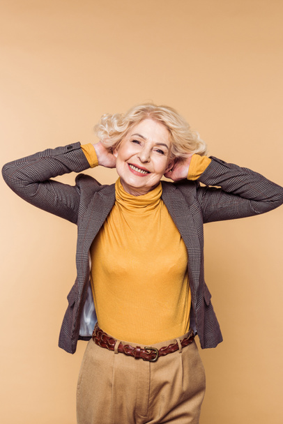 glücklich stilvolle Seniorin posiert isoliert auf beigem Hintergrund  - Foto, Bild