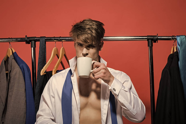 Homme d'affaires boire du thé ou du café dans la garde-robe sur fond rouge
 - Photo, image