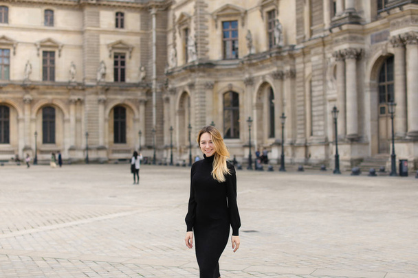 Γυναίκα που φοράει μαύρο φόρεμα στέκεται κοντά στο Λούβρο του Παρισιού. - Φωτογραφία, εικόνα
