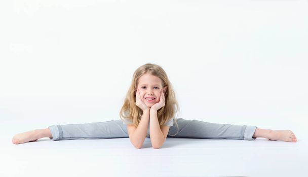 Little girl is sitting on a gymnastic twine. - Foto, afbeelding