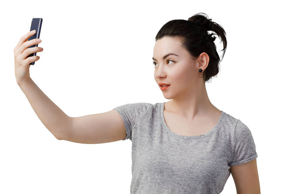 Immagine di giovane donna asiatica in piedi isolato su sfondo grigio scuro parete guardando da parte fare selfie da smartphone
. - Foto, immagini