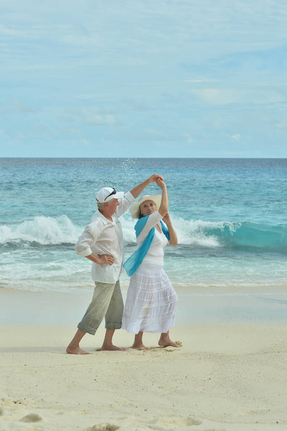 Gelukkig bejaarde echtpaar rusten op het strand dansen - Foto, afbeelding