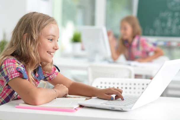 Cute little girl doing homework with laptop at home - Foto, Bild
