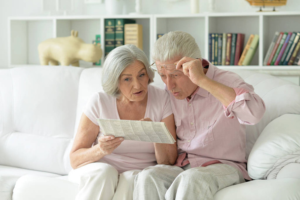 Close-up portrait of a  senior couple with newspaper  at home  - 写真・画像