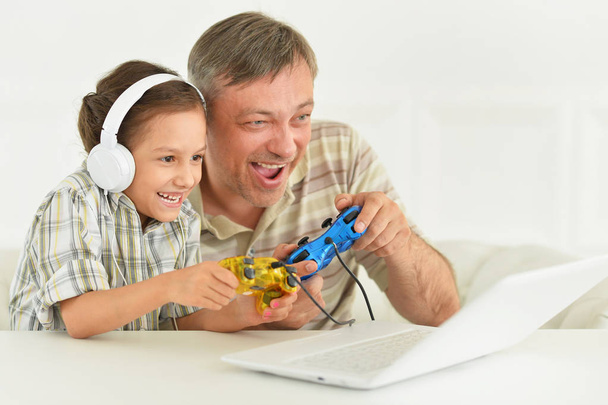 Father and daughter playing computer game with laptop - Foto, Imagem