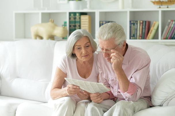 Close-up portrait of a  senior couple with newspaper  at home  - Fotoğraf, Görsel