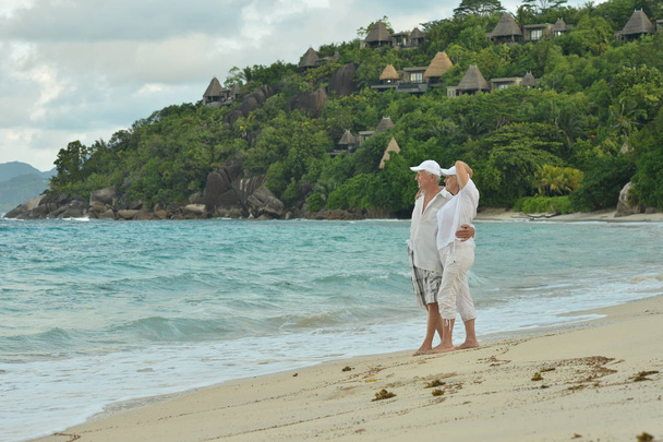 feliz casal de idosos andando na praia tropical
  - Foto, Imagem